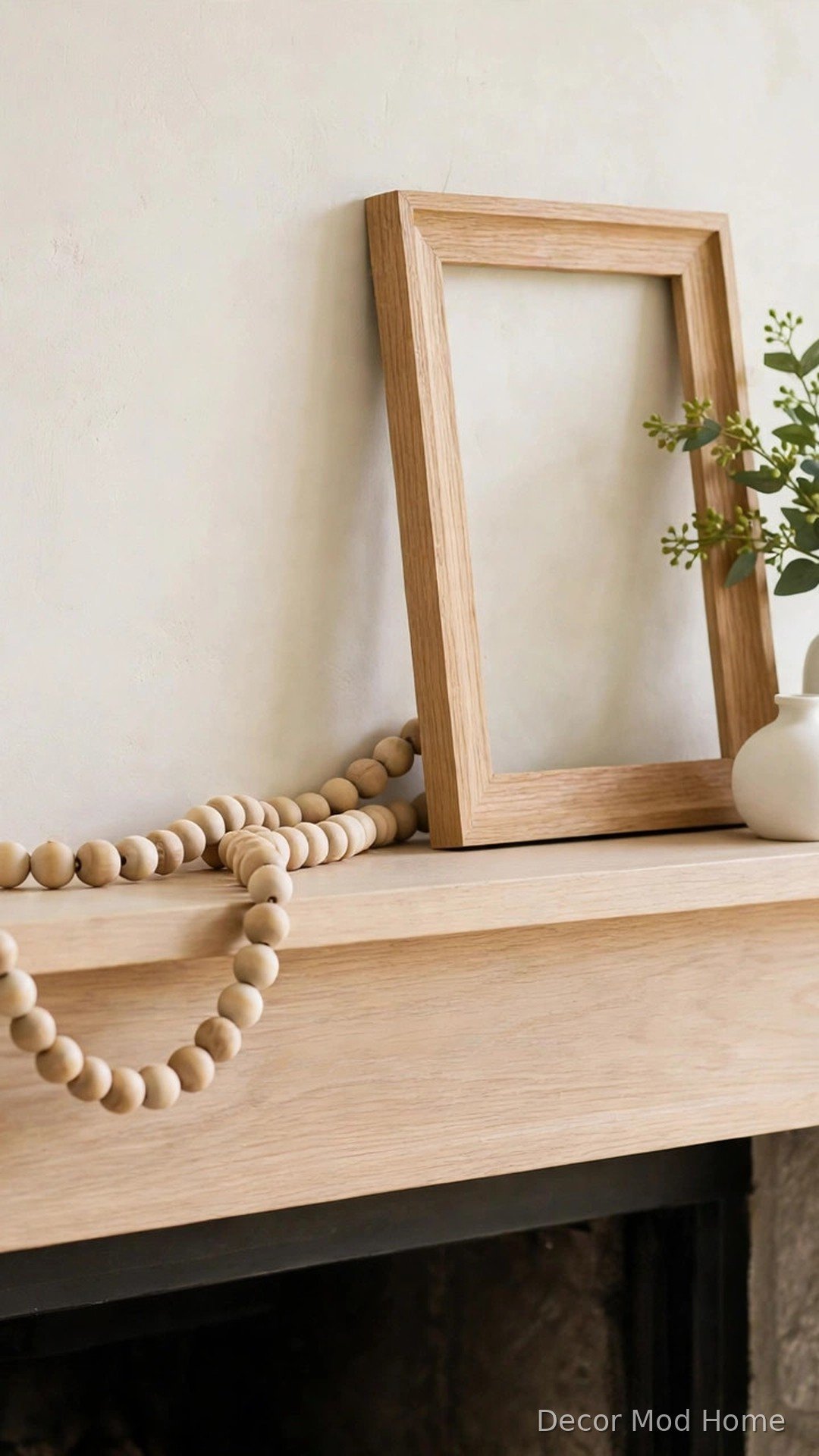 Wooden bead garland and light oak frame with white vase and greenery on a spring mantel