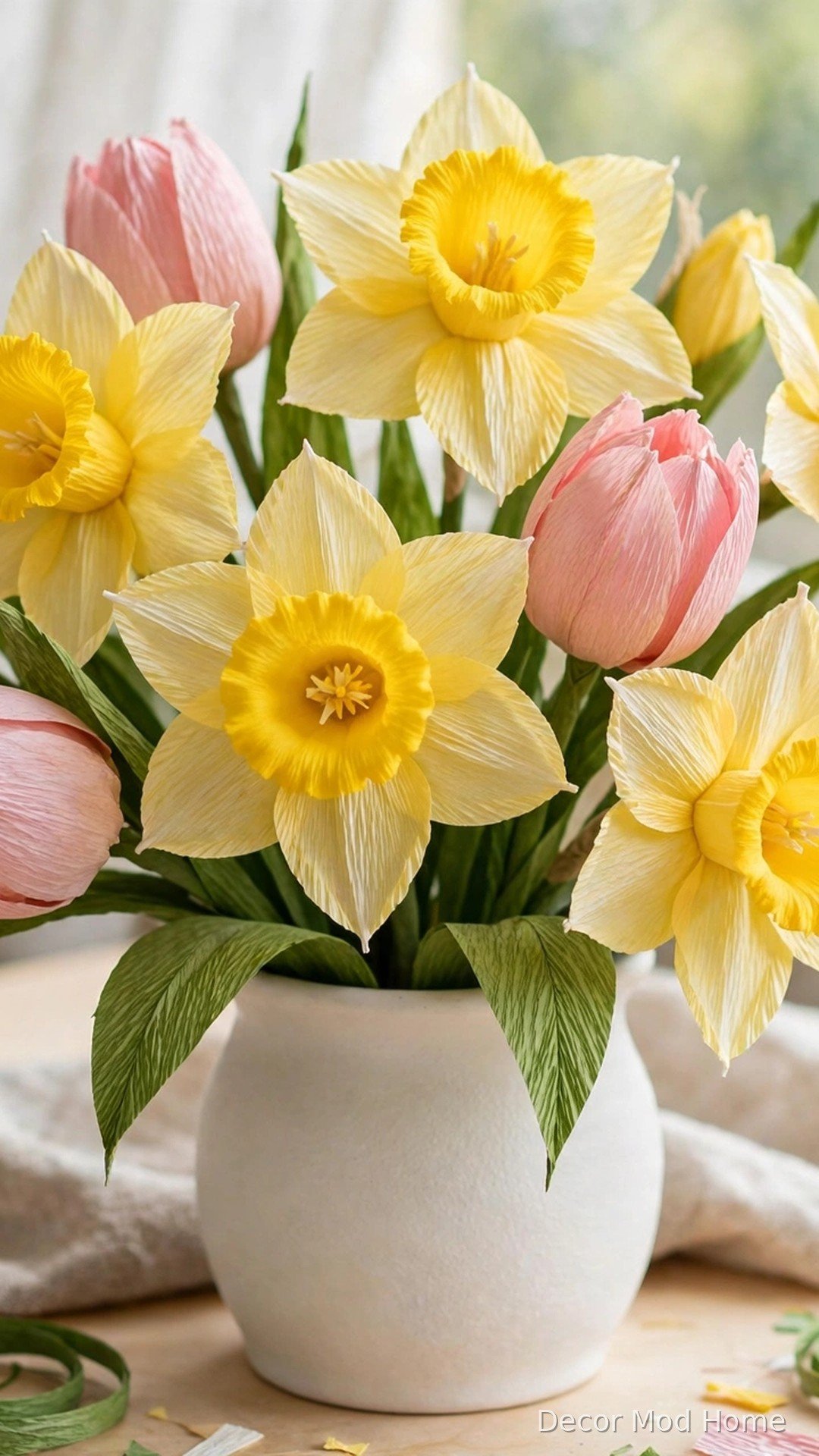 Handmade crepe paper daffodils and tulips arranged in a white ceramic vase