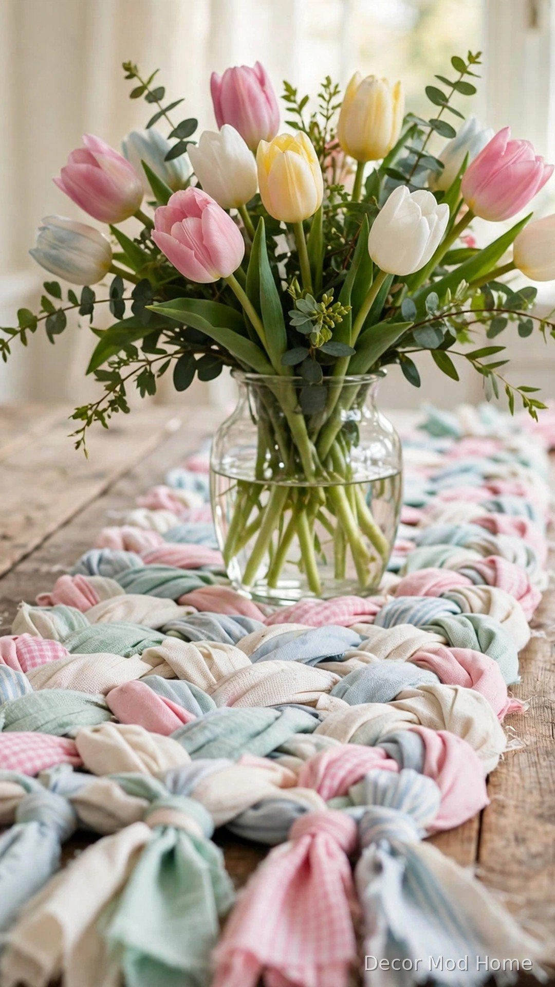 Braided rag runner woven from pastel fabric strips on a farmhouse dining table with tulips