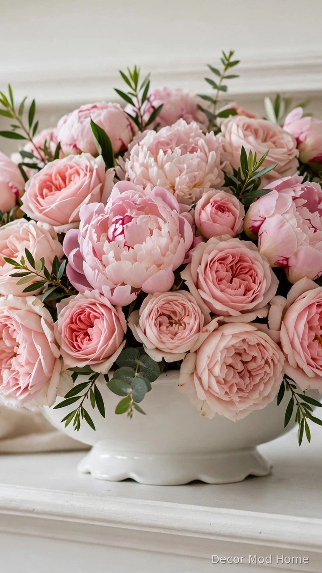 Blush peonies and garden roses in a low white footed compote on a mantel